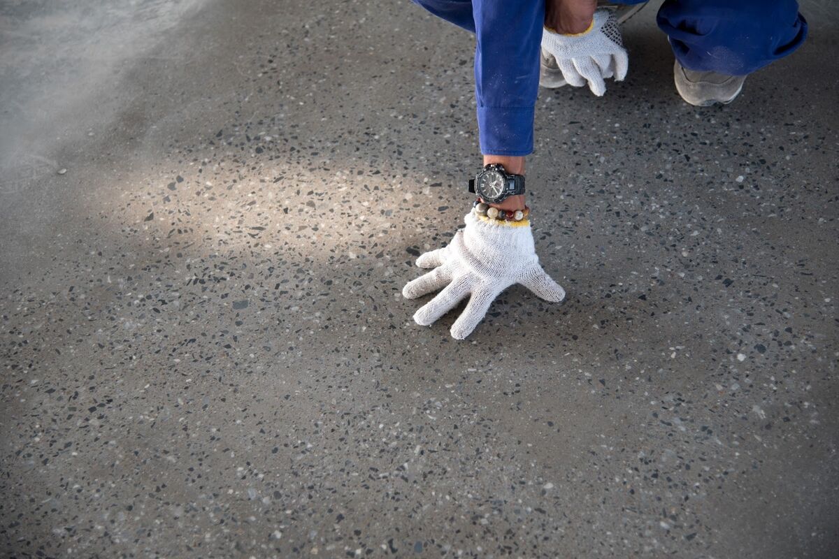 Person feeling concrete floor coating