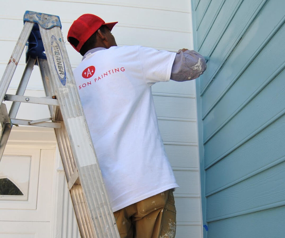 Man painting the outside of a house blue
