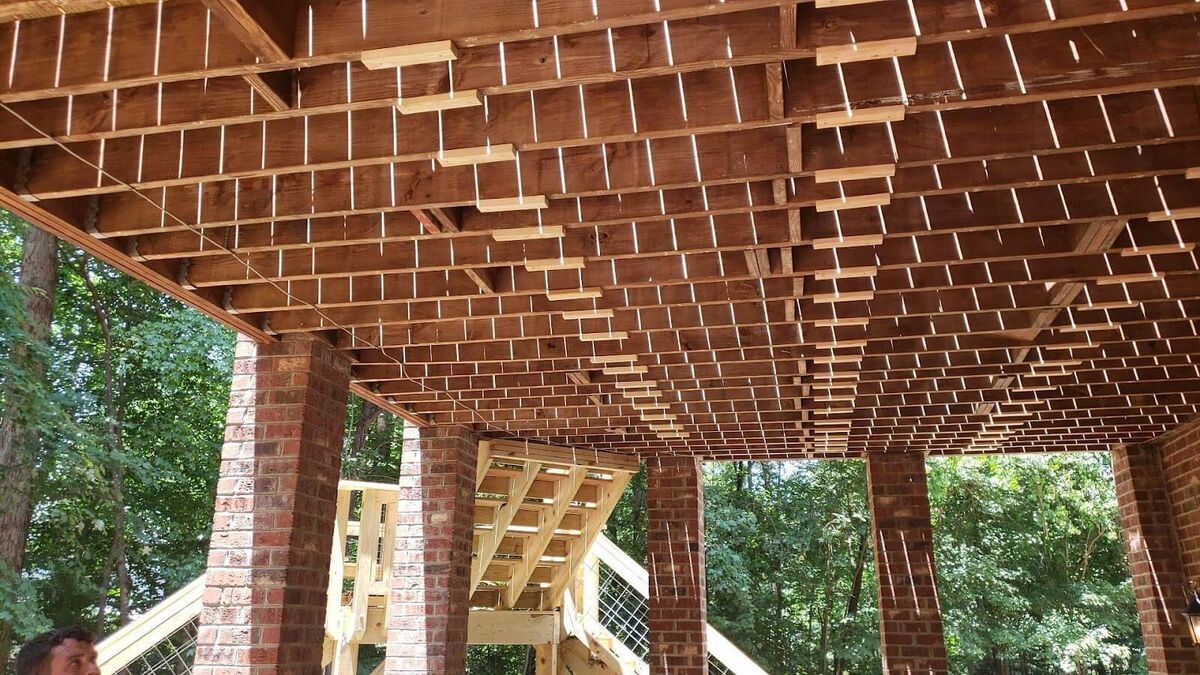 A wooden deck with brick columns and wooden beams.